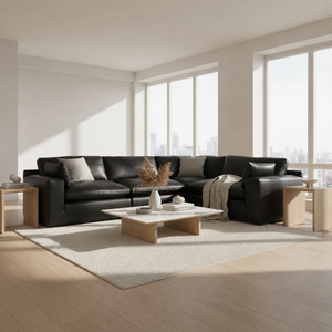 A modern black leather sectional sofa in a bright, minimalist living room with light wood floors, a white rug, and large windows. Signature Design by Ashley Emilia 