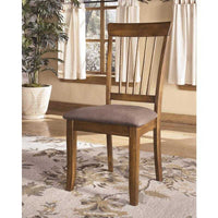 Wooden Ashley Furniture dining room chairs with cushioned seat in a light brown dining room setting